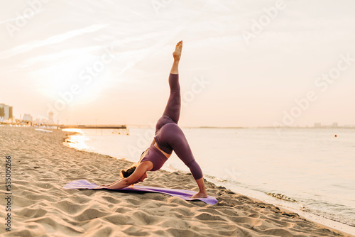Caucasian woman practicing yoga at seashore sandy beach on sunrise. Womens health and wellness. Sports body positive. Real instructor poses