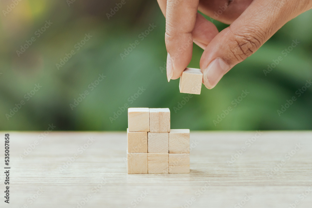 Hand putting and arranging blank wooden cubes on table with copy space. wooden cube blocks with nature background. Hand putting and arranging blank wooden cubes on table with copy space. wooden cube blocks with nature background.