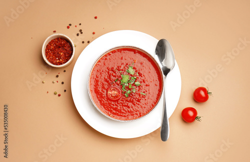 Obraz na plátně Bowl of tasty tomato soup and spices on color background