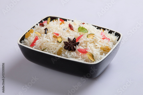 Star anise placed on cooked rice with use of selective focus on a particular part of the star anise with rest of the star anise, the cooked rice and background blurred.