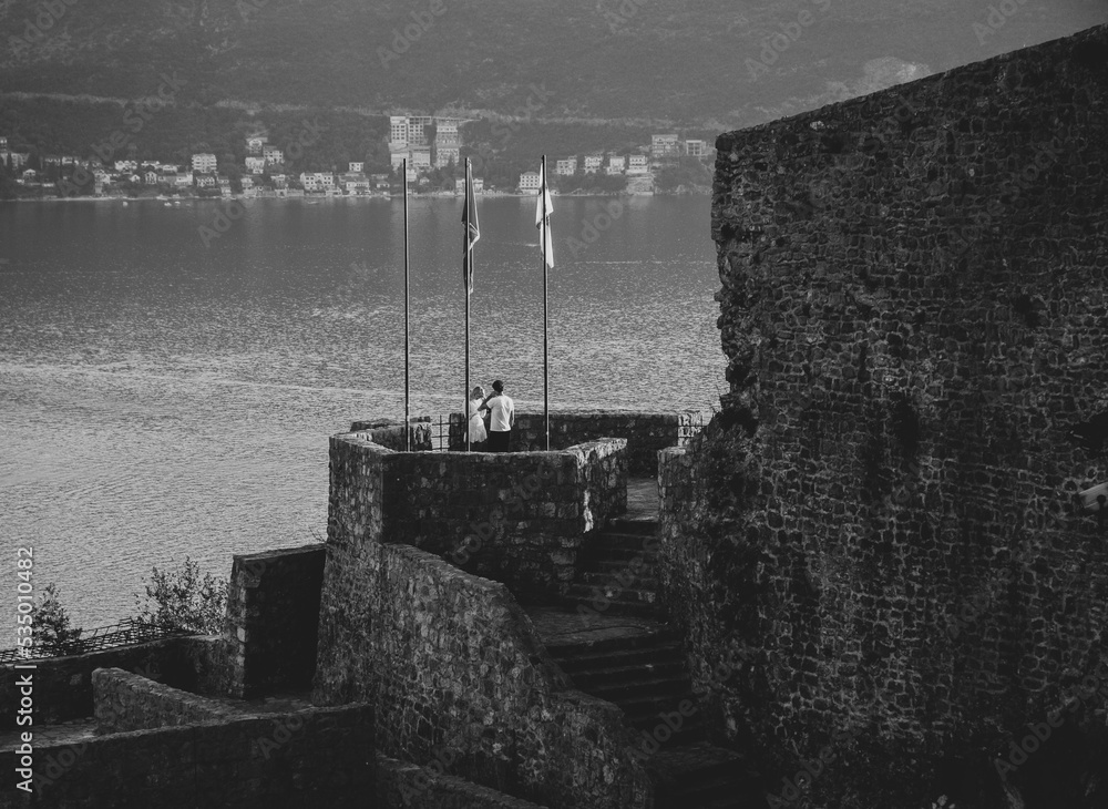 Obraz premium A young woman and man on the fortress next to the sea.