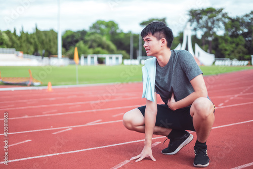 Exhausted man resting after jogging in the stadium during day.