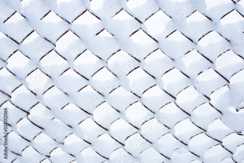 Iron mesh netting covered with white snow. Winter background