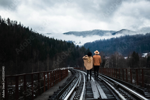 couple on railway station,travel, pancho style, couple in hats, mountains photo