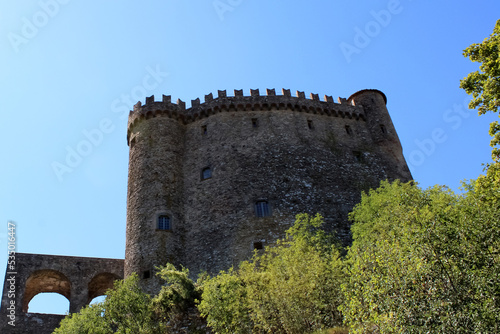 I merli a coda di rondine del Castello di Fosdinovo stagliati nel cielo con alberi photo