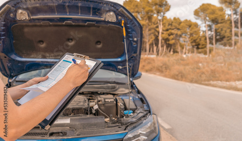 Técnico irreconocible, apuntando los daños del motor del automóvil. Fotografía horizontal con espacio para texto.