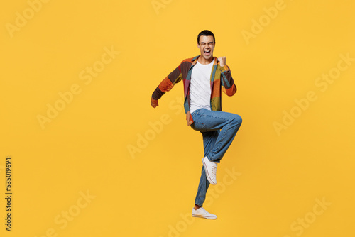 Full body young fun middle eastern man 20s wear casual shirt white t-shirt doing winner gesture celebrate clenching fists say yes isolated on plain yellow background studio People lifestyle concept