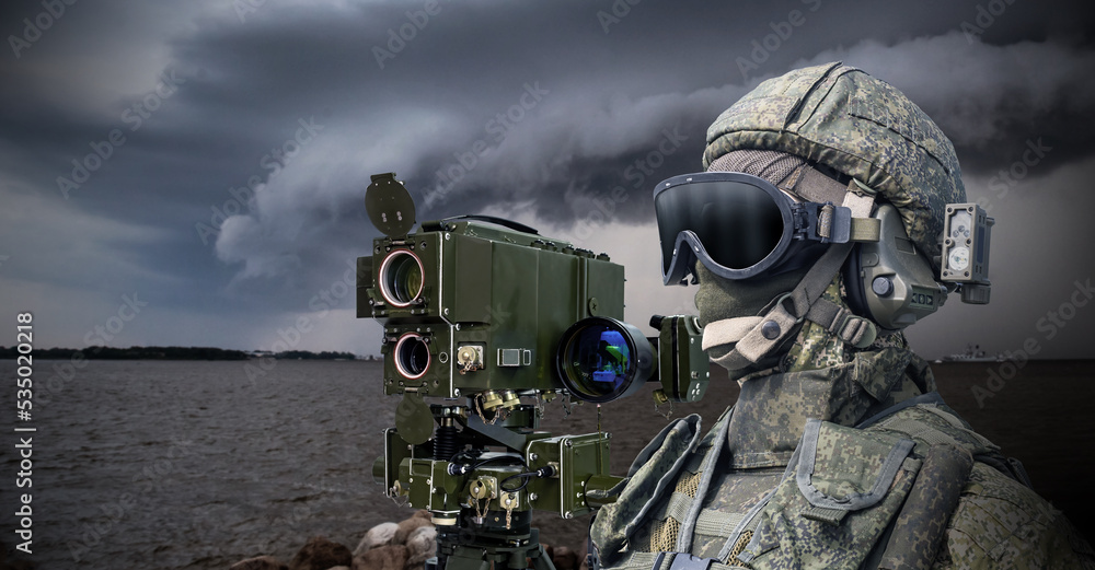 Navy soldier. Laser rangefinder next to soldier. Man in camouflage military uniform. Equipment for naval army. Soldier stands on bank of river. Military technologies. Warrior in face mask and helmet - obrazy, fototapety, plakaty 