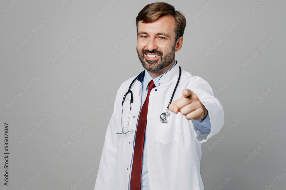Male doctor man wears white medical gown suit stethoscope work in hospital point index finger camera on you motivating encourage isolated on plain grey color background. Healthcare medicine concept. Male doctor man wears white medical gown suit stethoscope work in hospital point index finger camera on you motivating encourage isolated on plain grey color background. Healthcare medicine concept.