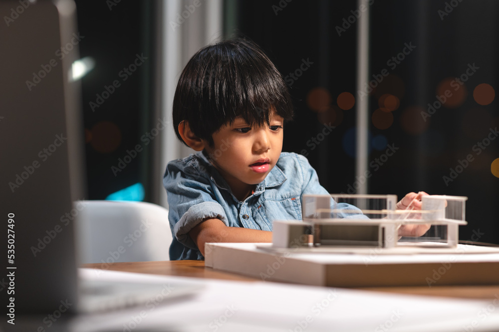 Inspiration kids in occupation in the future, Asian kid playing and concentrating to home model box in the job of parent at office room at night. Skill and learning practice of children's success. Inspiration kids in occupation in the future, Asian kid playing and concentrating to home model box in the job of parent at office room at night. Skill and learning practice of children's success.
