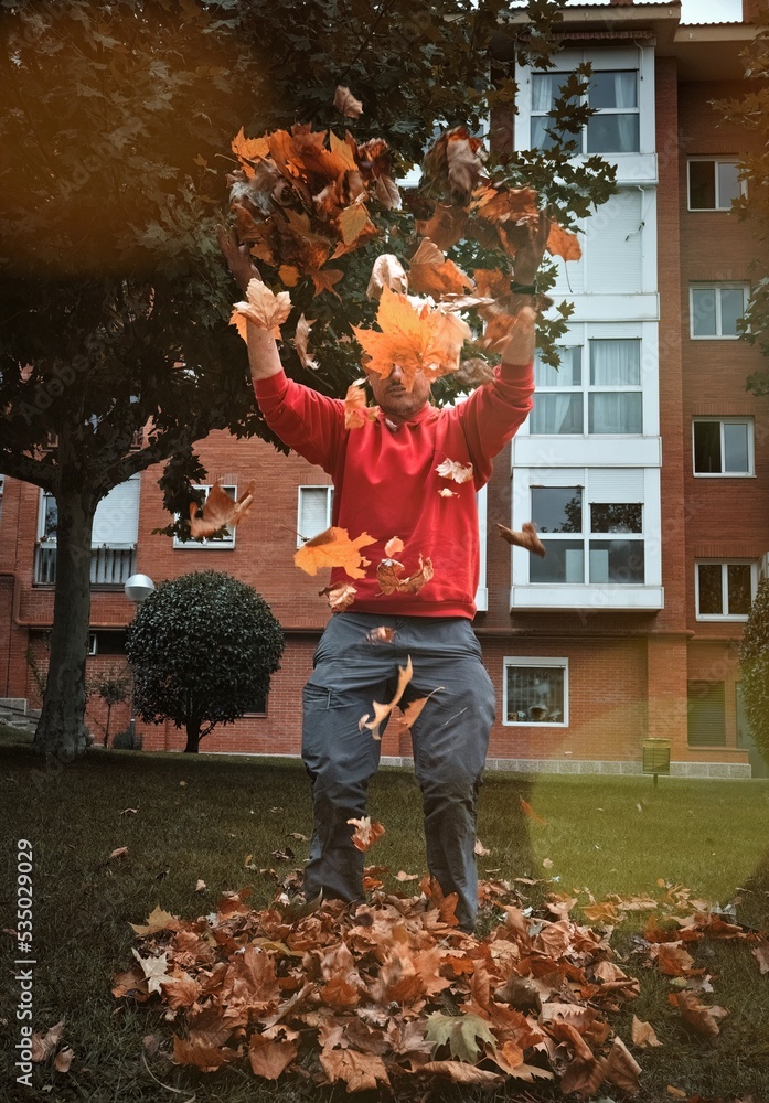 Gardener throwing autumn leaves into the air.
