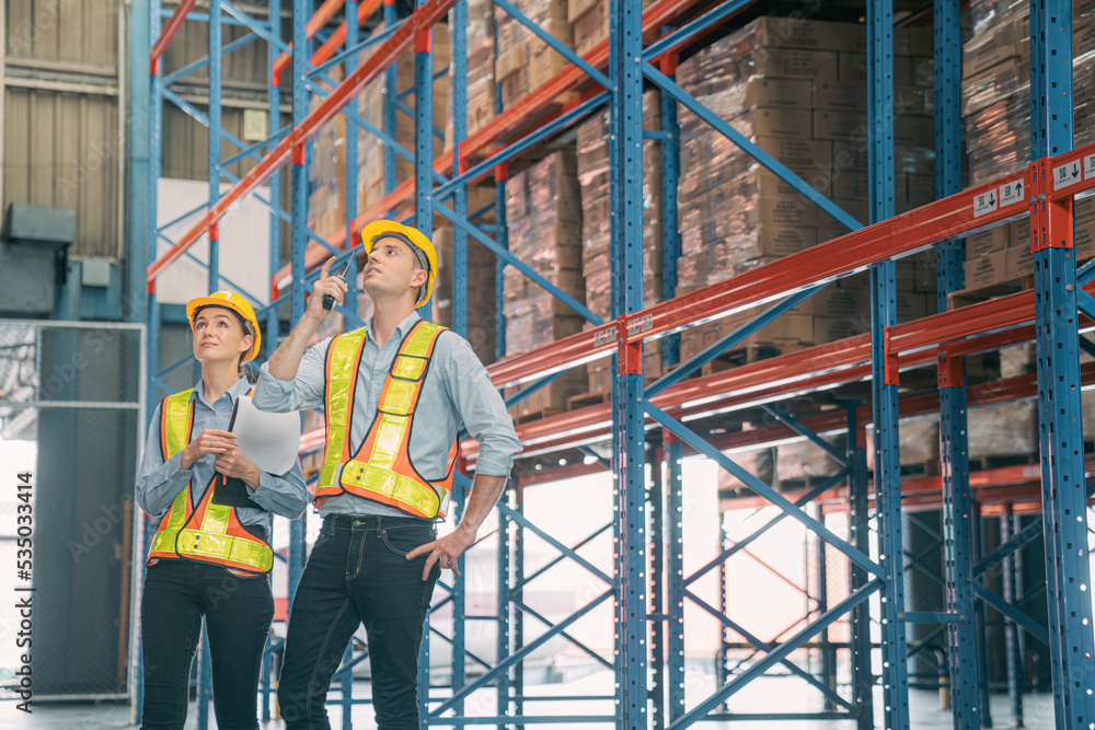 Caucasian man, woman warehouse supervisor wear safety discuss,talk and use clipboard check box package on shelf, product distribution inventory management,Logistics shipping business planning industry Caucasian man, woman warehouse supervisor wear safety discuss,talk and use clipboard check box package on shelf, product distribution inventory management,Logistics shipping business planning industry