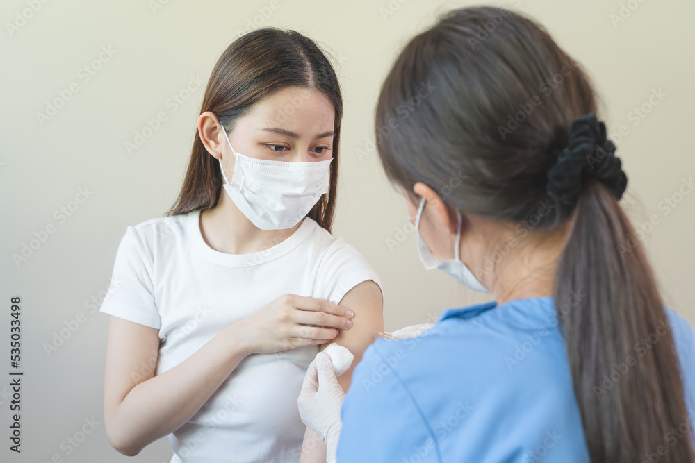 People getting a vaccination to prevent pandemic concept. Woman in medical face mask  receiving a dose of immunization coronavirus vaccine from a nurse at the medical center hospital