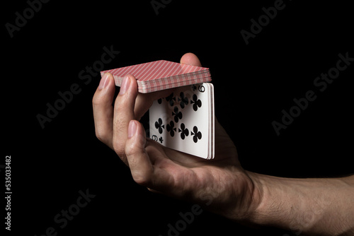 A man's hand holds playing cards on a black background. Gambling concept © Ruzanna