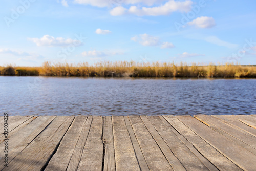 Closeup view of wooden pier near river on sunny autumn day