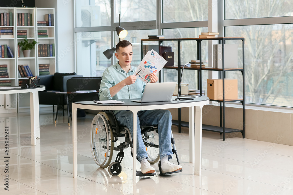 Young man in wheelchair working in office Young man in wheelchair working in office