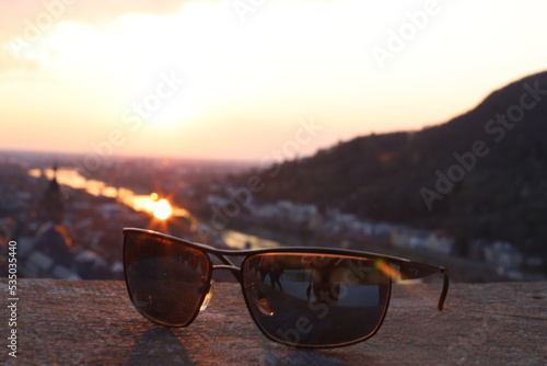 View over Heidelberg in the evening. Sunset on the horizon, view over the old town, the castle and the river Neckar on a warm summer day in the foreground sunglasses