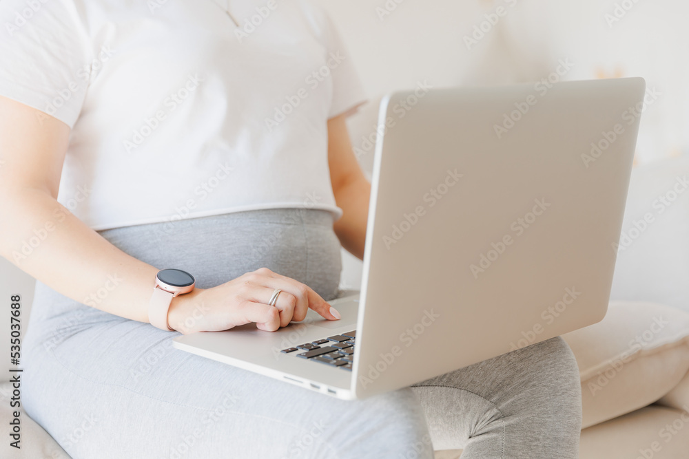Closeup hand of pregnancy woman using online laptop on sofa with sunlight Closeup hand of pregnancy woman using online laptop on sofa with sunlight