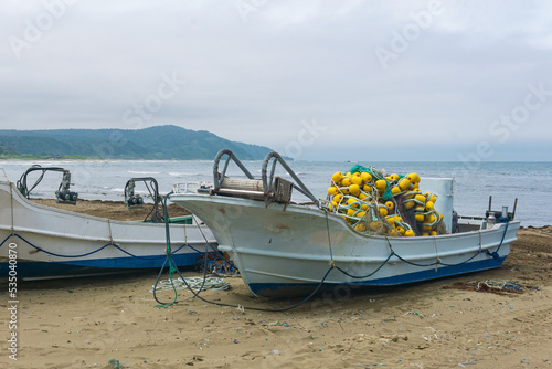 small fishing boats with a net on board on the seashore photo