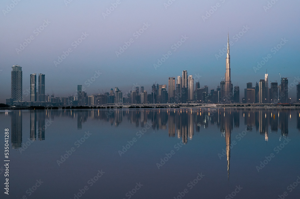 Dubai city skyline reflecting on the water surface during sunset