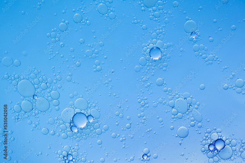 Oil and water bubbles on blue background. Abstract face cleanser bubbles background.