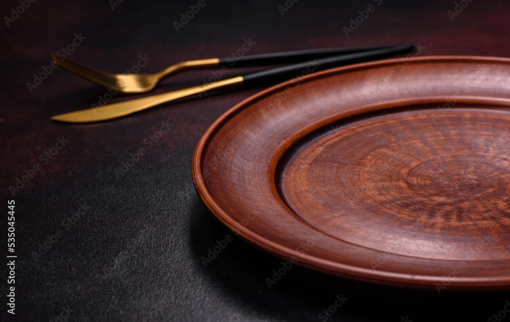 Obraz premium An empty brown ceramic plate on a dark concrete brown background