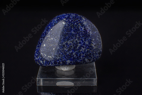 Stone from the mineralogical collection. Pebbles of lapis lazuli interspersed with pyrite on a black background.