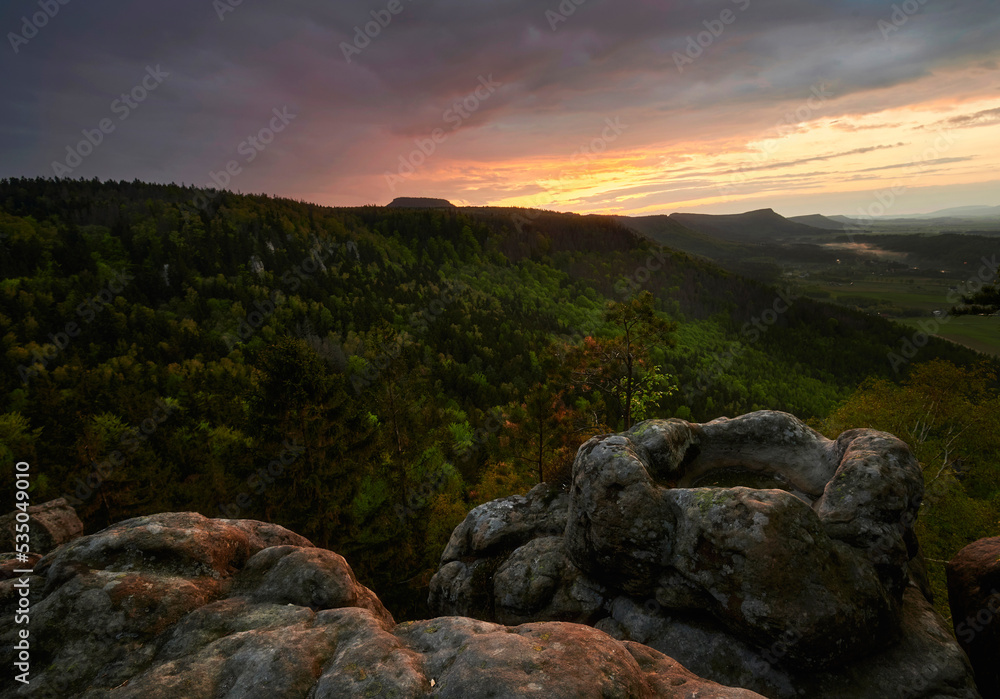 Sunset over the table mountains in Poland with rocky pond in the foreground





