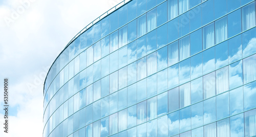 Tall generic corporate office building exterior, square glass windows reflecting clouds, bright white blue wide slide background, copy space, nobody. Modern business architecture, cloud reflections