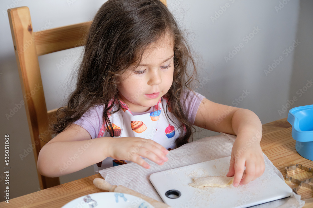 Young girl playing chef at the kitchen table Young girl playing chef at the kitchen table