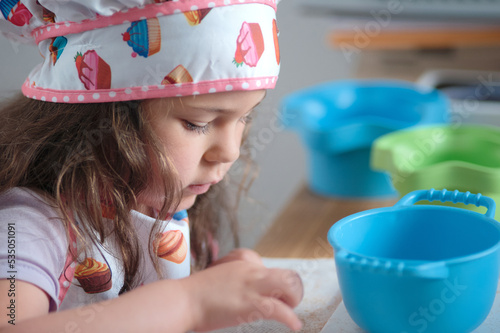 Young girl playing chef at the kitchen table photo