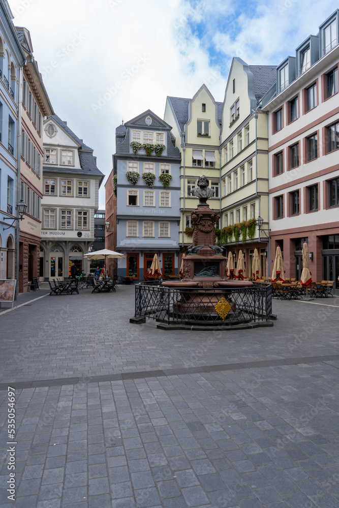 Square in the center of Frankfurt, with the typical German houses, with some terraces and with a statue in the middle.