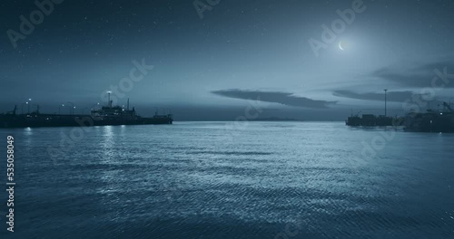 Crescent moon above ocean fishing boat port aerial view. Blue light starring night on sea water background. Harbor silhouette on midnight horizon. Hawaii vacation travel. Halloween atmosphere concept. photo