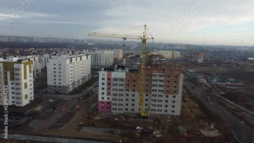Construction of new residential high-rise buildings. Hoisting crane and new multi-storey buildings. Industrial aerial view.