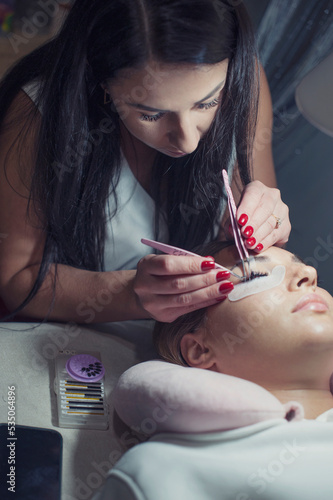 Woman master in salon making eyelash extension