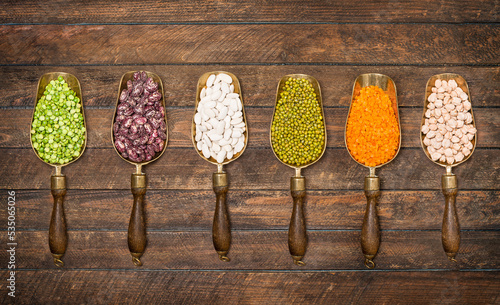 Raw dried legumes in vintage scoops on wooden background top view. Set or coolection of legumes. photo