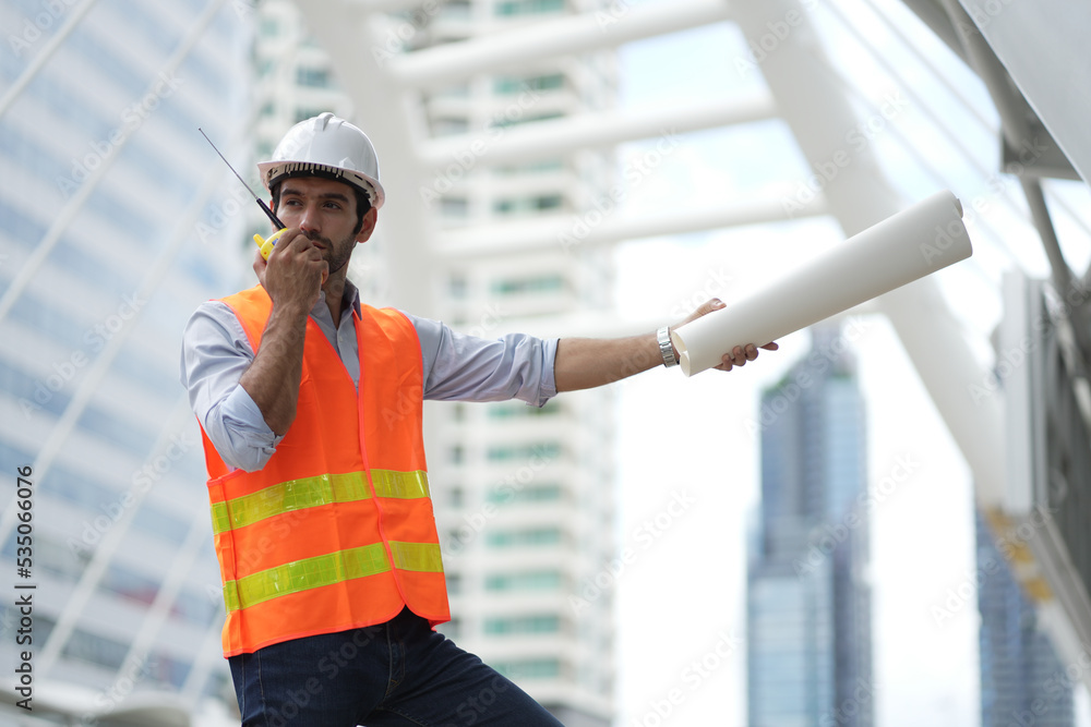 Caucasian engineer handsome man or architect looking forward with white safety helmet in construction site. Standing at modern building construction. Worker asian man working project building.