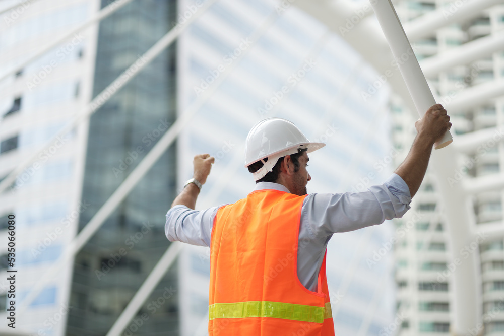Caucasian engineer handsome man or architect looking forward with white safety helmet in construction site. Standing at modern building construction. Worker asian man working project building. Caucasian engineer handsome man or architect looking forward with white safety helmet in construction site. Standing at modern building construction. Worker asian man working project building.