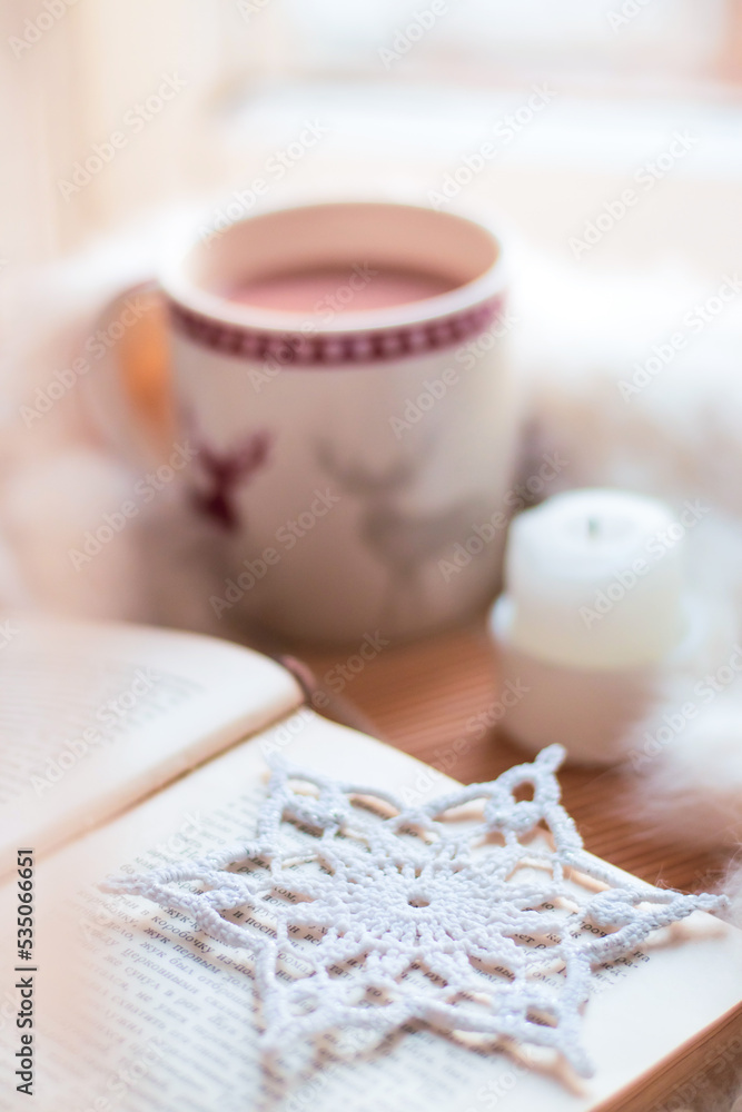 christmas still life. cup of cocoa, open book, white blanket, candle, handmade snowflake on windowstill near light window, selective focus christmas still life. cup of cocoa, open book, white blanket, candle, handmade snowflake on windowstill near light window, selective focus