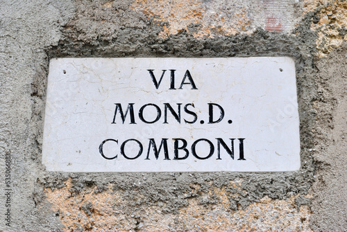 Close Up of Old Italian Stone Street Name Translated as 'Mister D Comboni Street' 