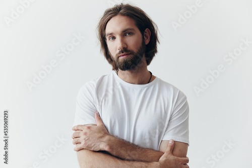 Murais de parede Portrait of a man with a black thick beard and long hair in a white T-shirt on a
