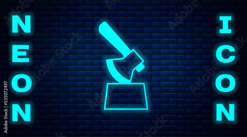 Glowing neon Wooden axe in stump icon isolated on brick wall background. Lumberjack axe. Axe stuck in wood. Chopping wood. Vector
