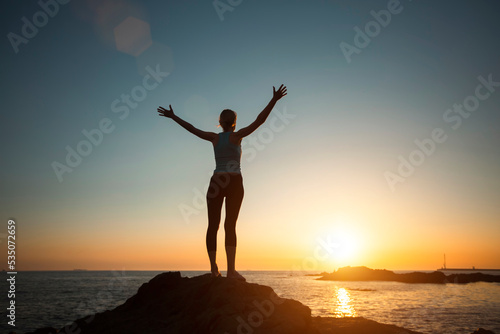 Silhouette of a yoga woman seeing off the sun on the ocean.