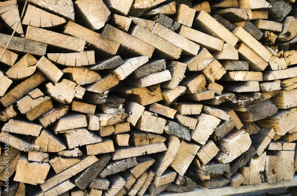 Chopped firewood stacked in a chaotic manner horizontally and vertically. The concept of winterizing wood heating and heat. Close-up, front view, pattern. Chopped firewood stacked in a chaotic manner horizontally and vertically. The concept of winterizing wood heating and heat. Close-up, front view, pattern.