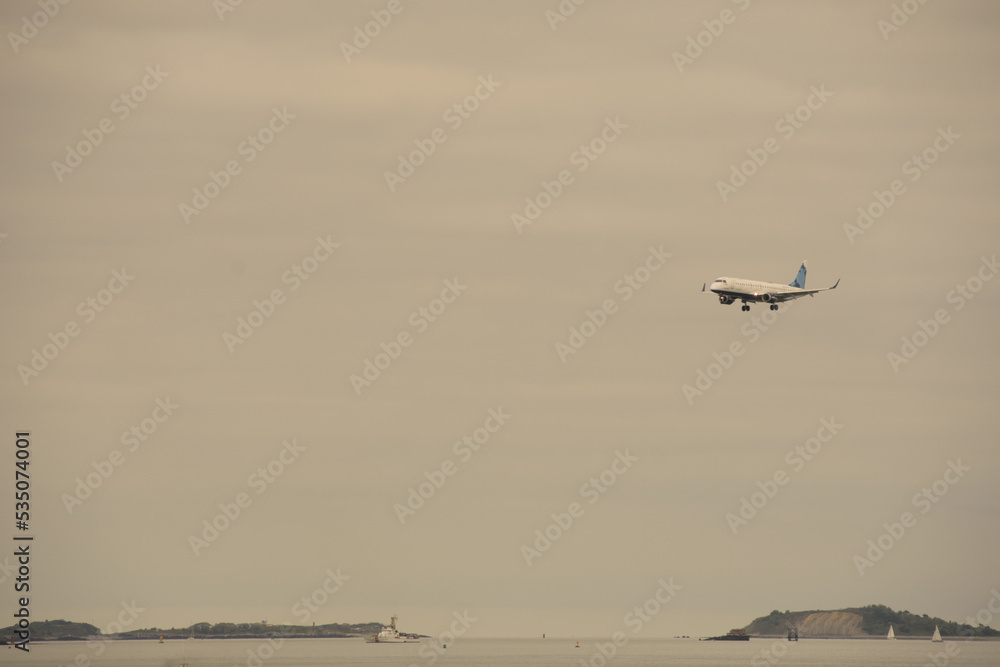 Airplane about to land at Boston, Massachusetts airport under cloudy skies Airplane about to land at Boston, Massachusetts airport under cloudy skies