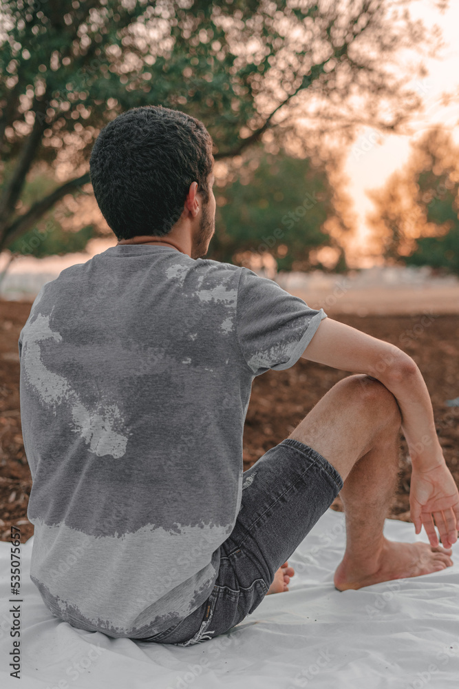 Fototapeta premium Young Arab model sitting on a white picnic blanket outdoors