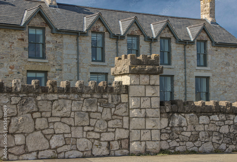 Pale coloured stone wall with a building behind