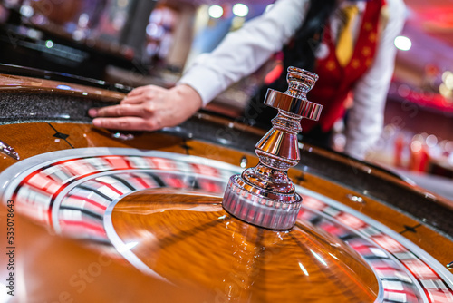 The dealer holds a ball and spins the roulette wheel in a casino. photo