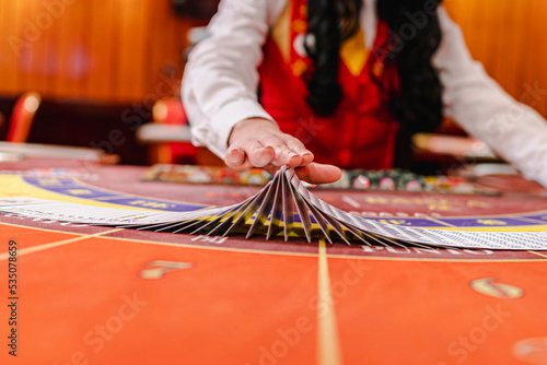 Croupier holding cards, behind a gaming table in a casino.