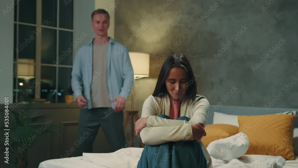 Multiracial couple quarreling in the bedroom at night.